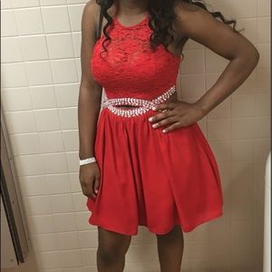 A cute short, red prom dress with lace and jewels.